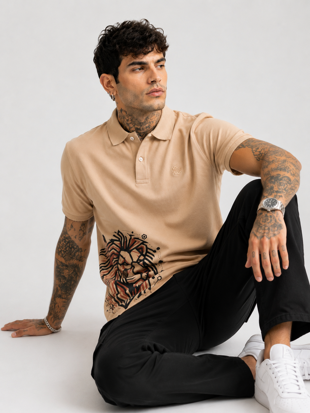 Beige polo shirt with lion graphic on hemline, short sleeves and button collar
