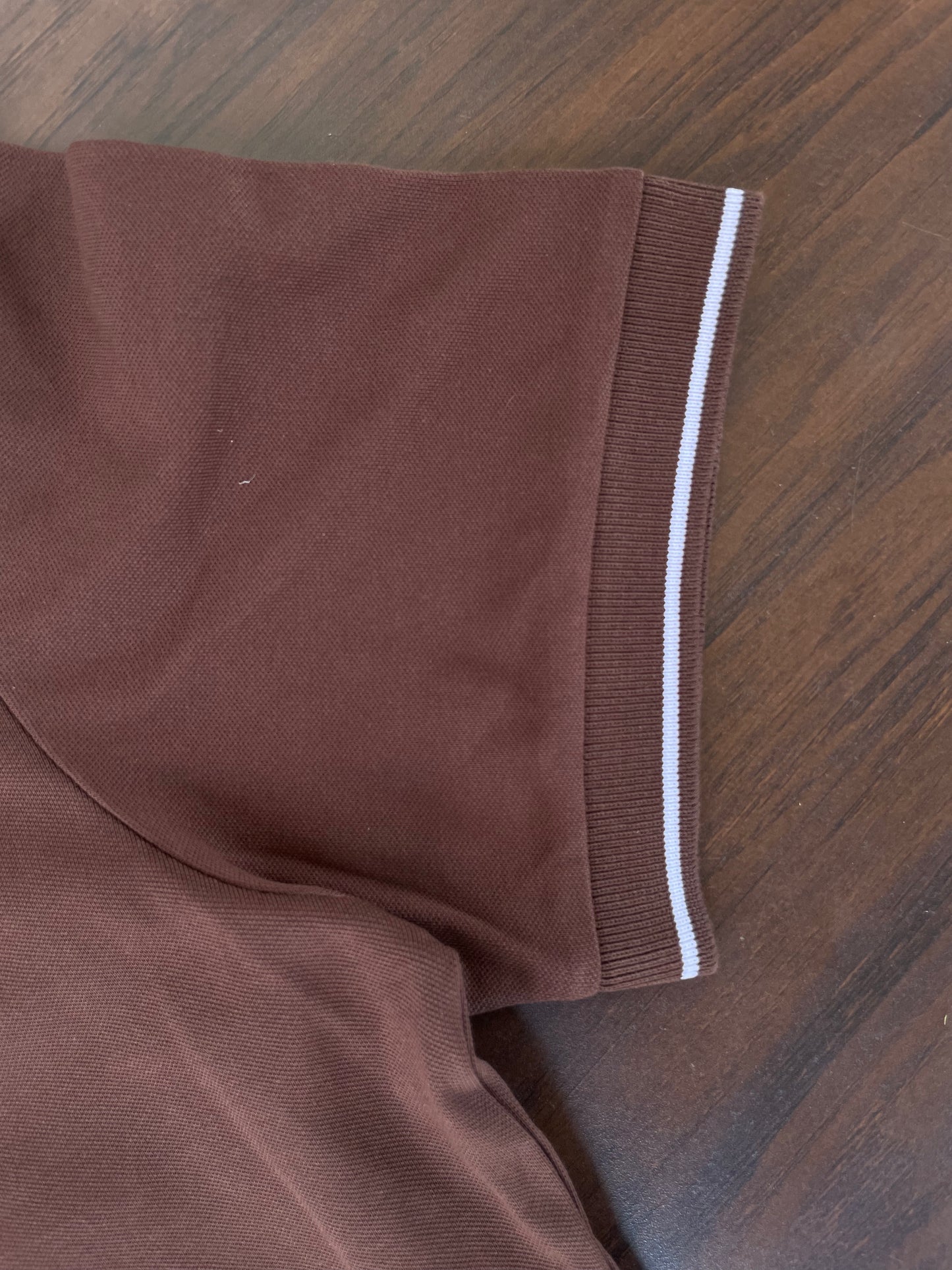 Brown polo sleeve cuff with white contrast stripe and smooth knit fabric