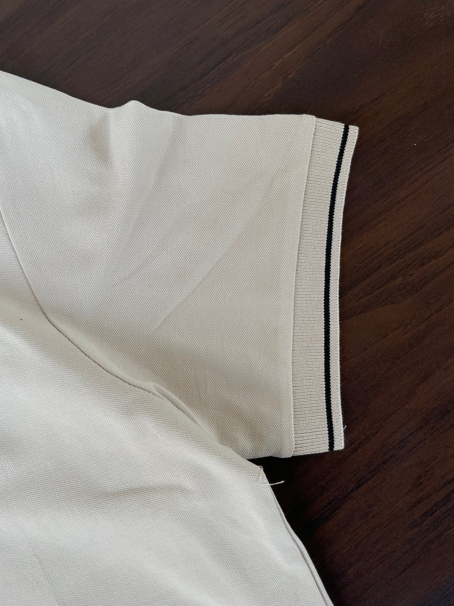 Cream polo shirt sleeve cuff with navy side stripe trim