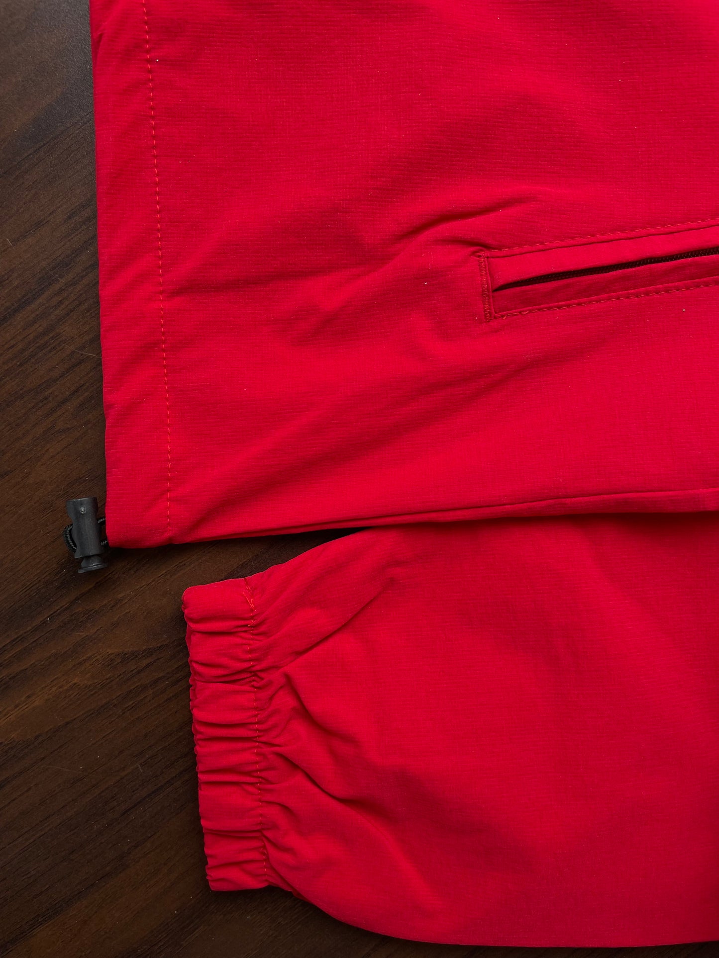 Scarlet red windbreaker hem with elastic cuffs, close-up on front and sleeve