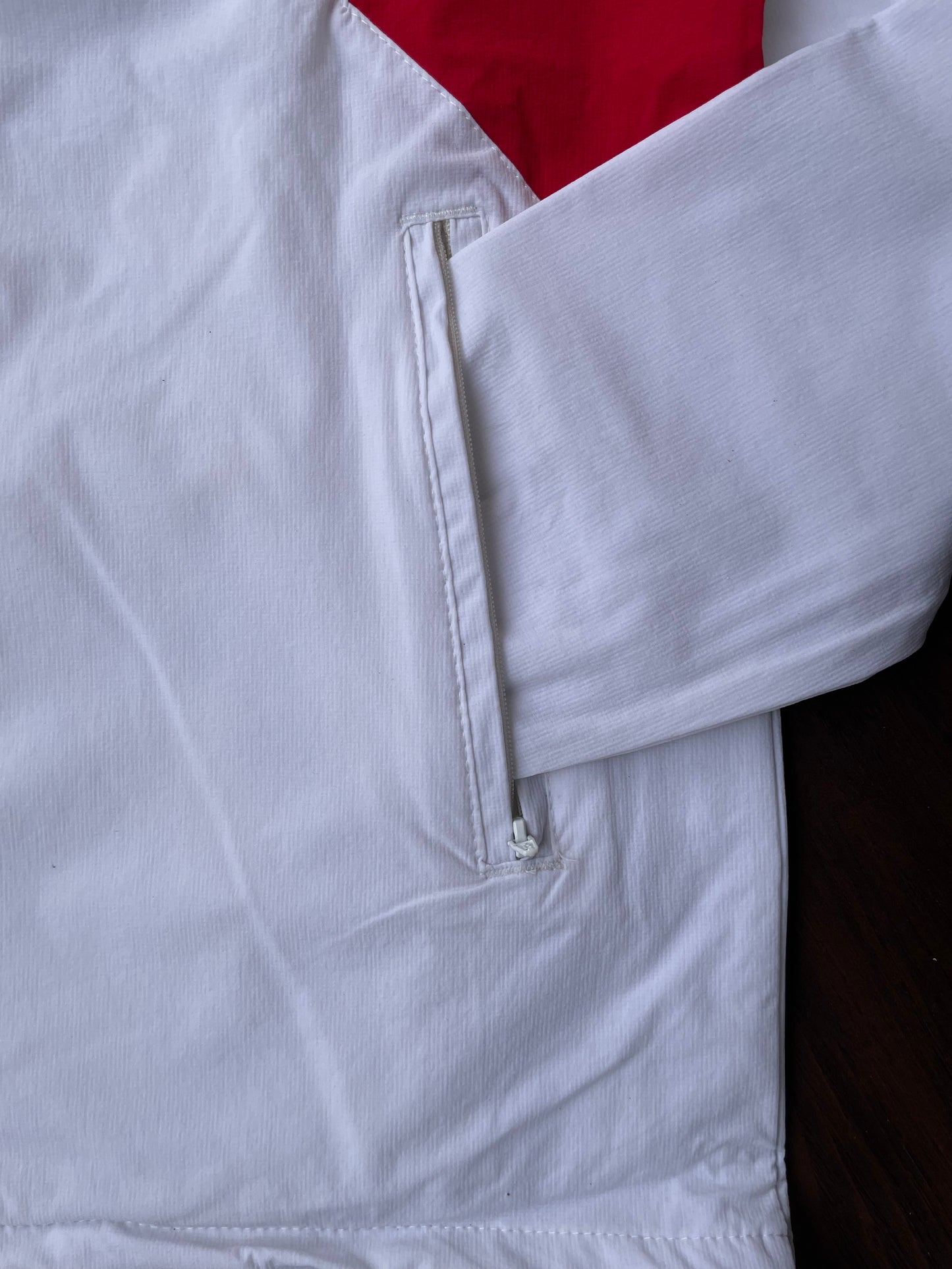 White windbreaker sleeve cuff with elastic seam and zippered pocket detail
