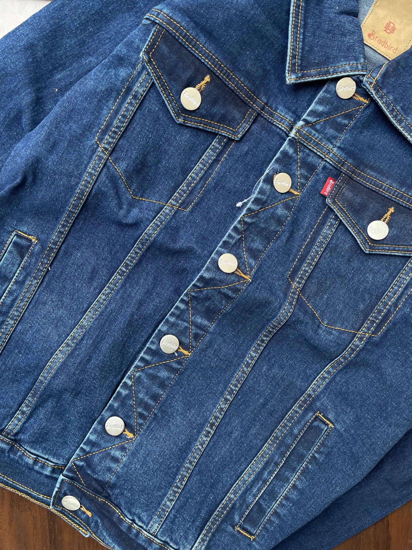Dark-wash denim jacket back yoke and pockets close-up with buttons and seams