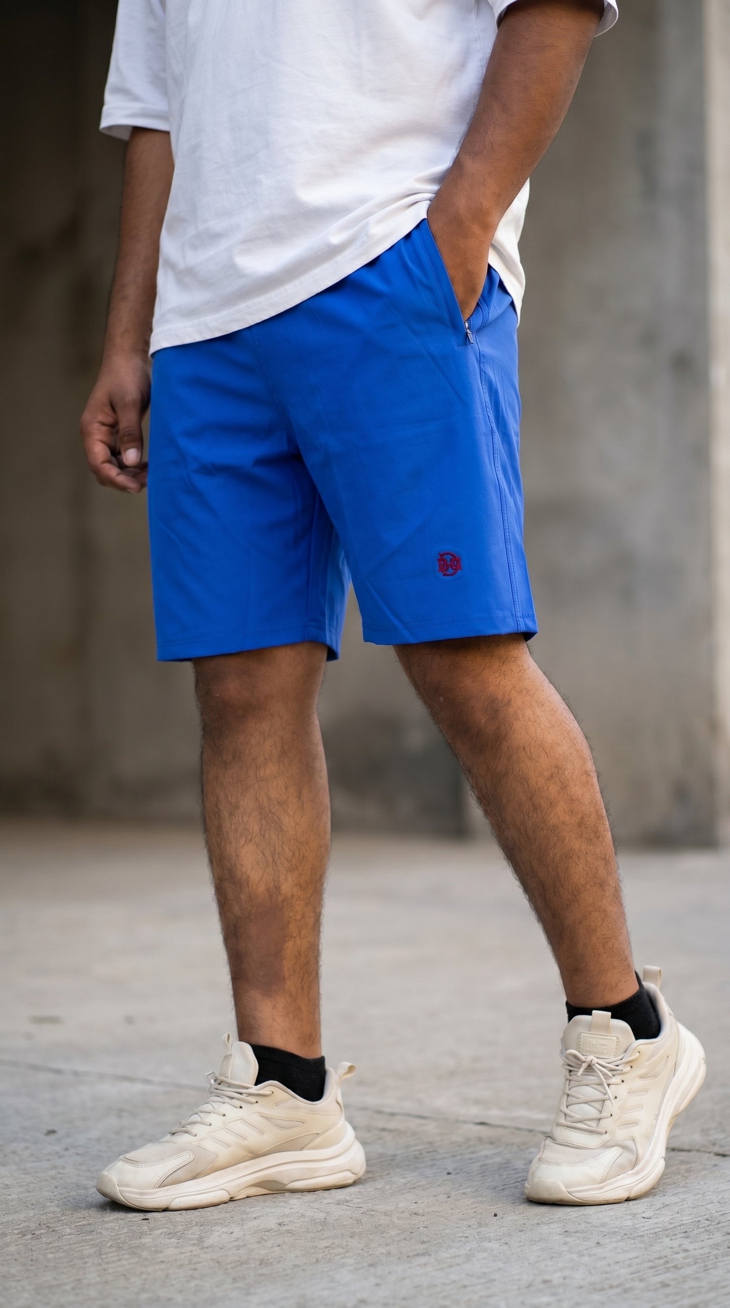 Blue shorts with red logo patch and drawstring-style waist, above-knee