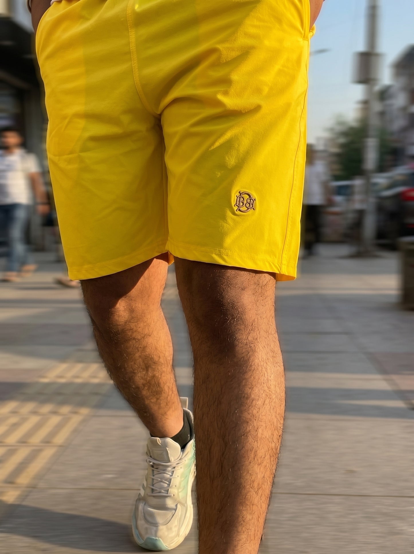 Bright yellow casual shorts, side logo on leg with stitched seams and mid-thigh length