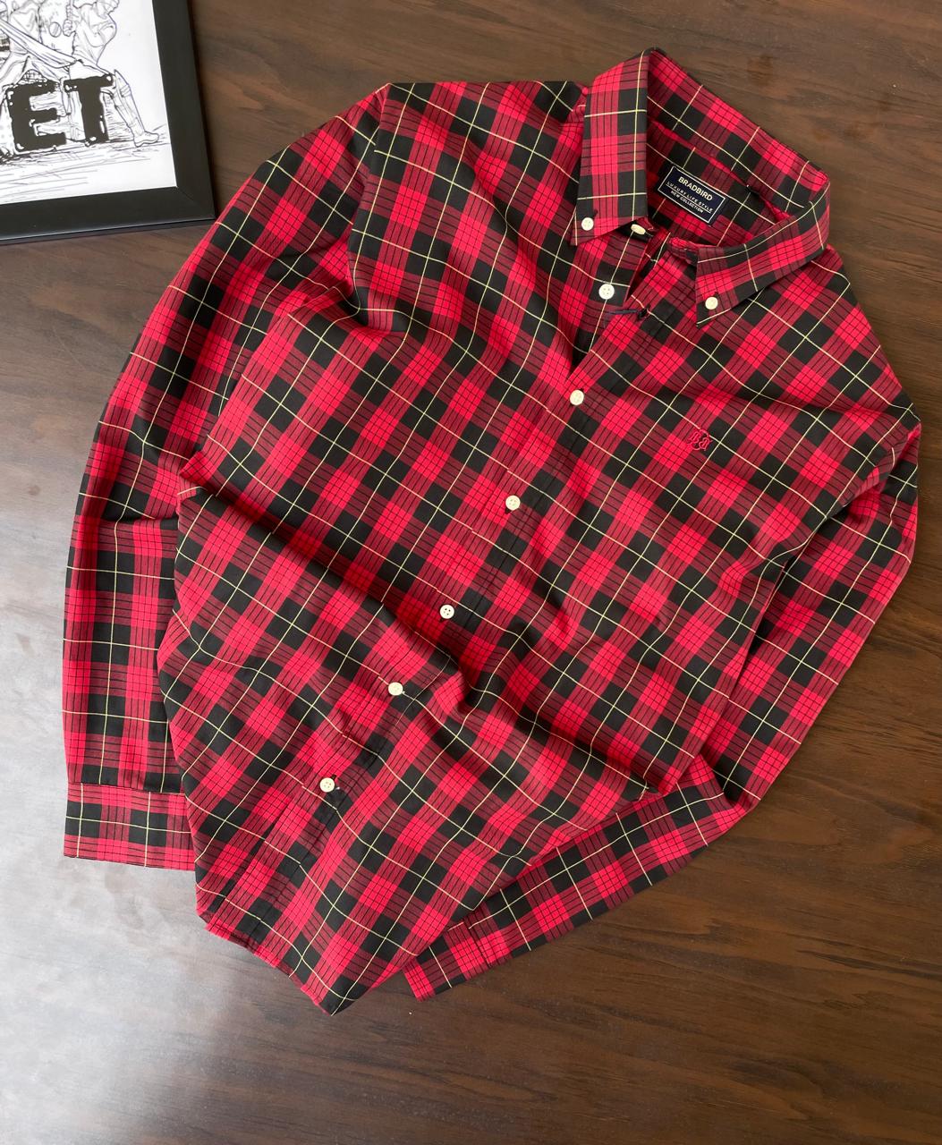 Buffalo check red and black button-up shirt with collar, laid folded on wood