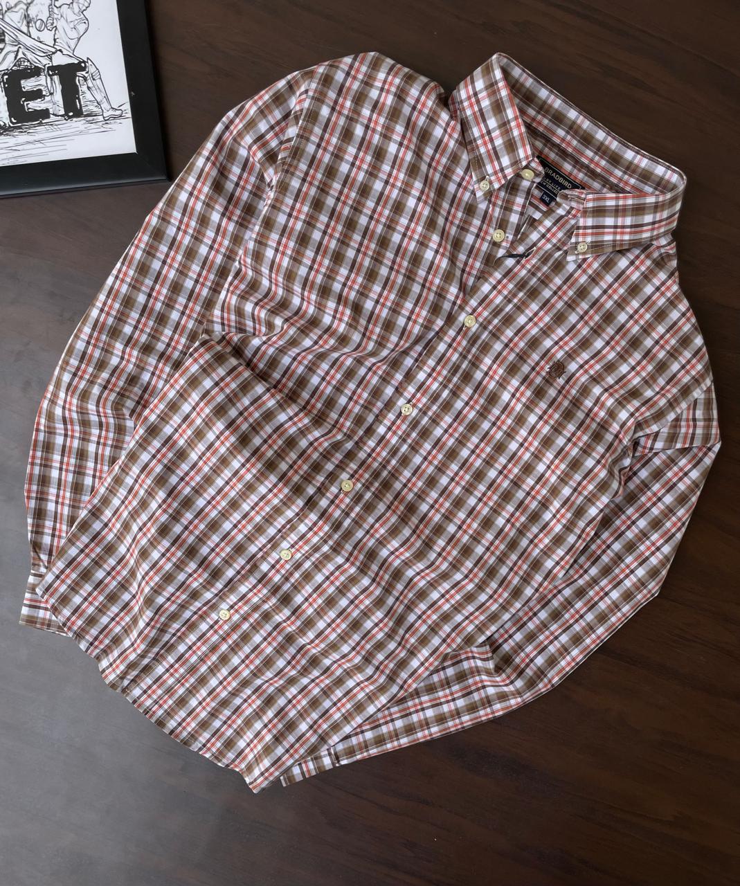 Folded brown, orange, and white plaid button-up shirt with collar and buttons