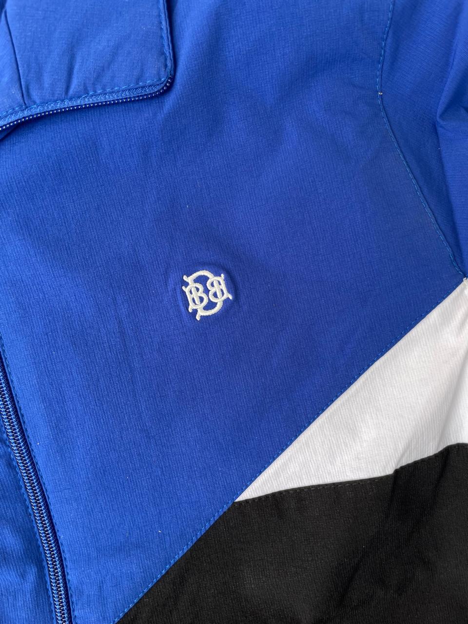 Close-up of royal blue front with small crest logo and white/black color-block panel