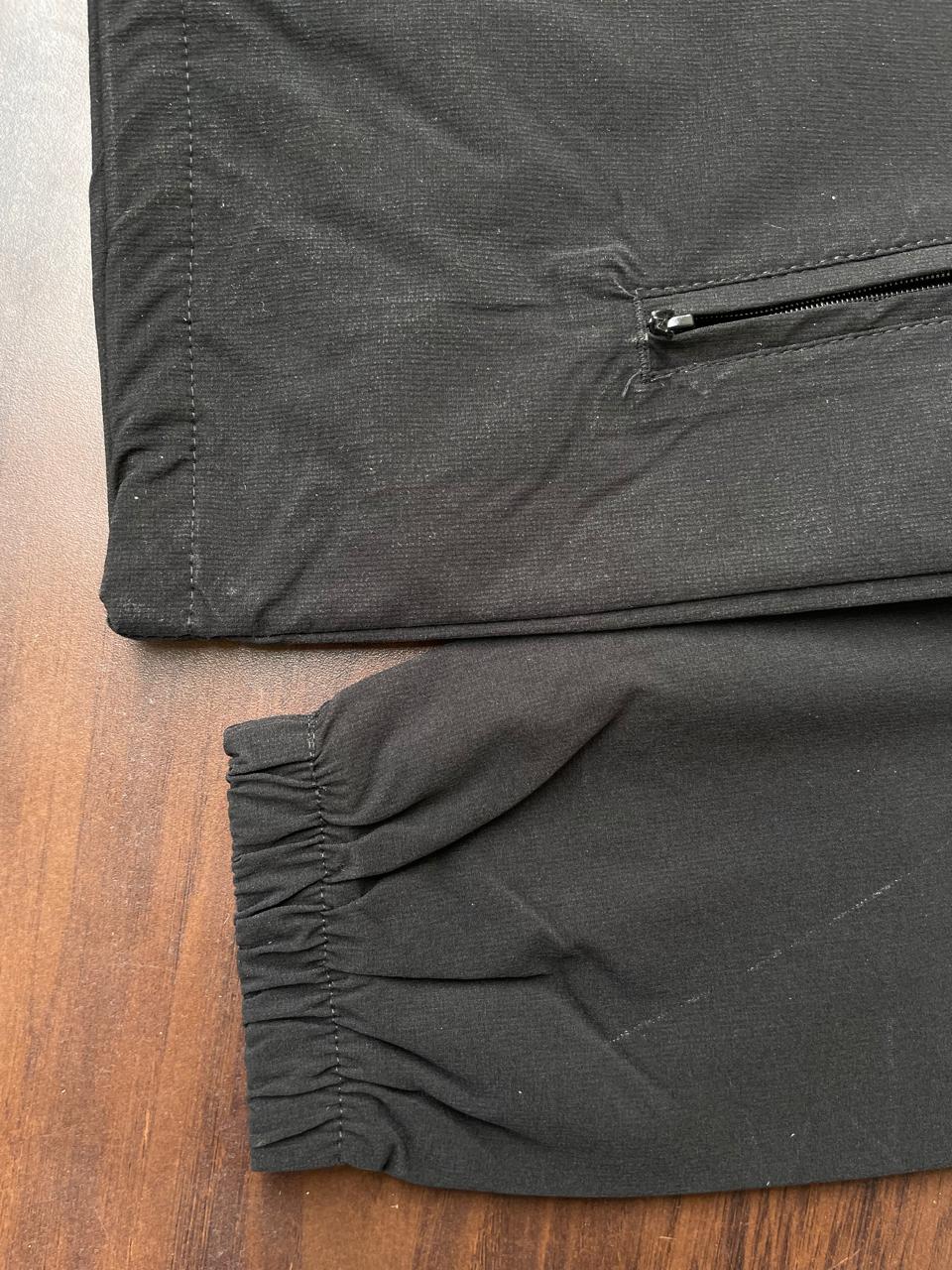 Black windbreaker elastic cuff and gathered hem with zipper pocket seam detail