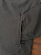 Dark windbreaker side pocket detail with zipper and seam stitching at hem