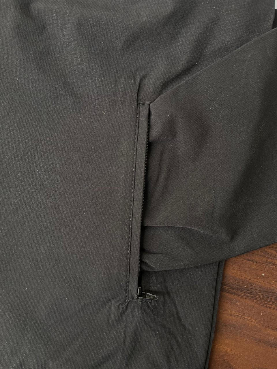 Dark windbreaker side pocket detail with zipper and seam stitching at hem