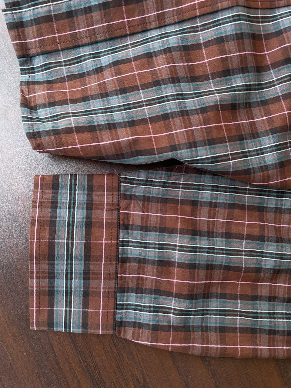 Sleeve cuff and hem detail on tan and slate grey tartan plaid button-up shirt