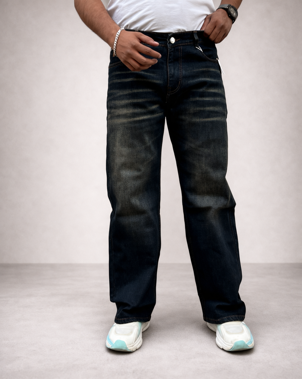 Back pocket close-up on dark indigo jeans: contrast orange stitching and curved seam.