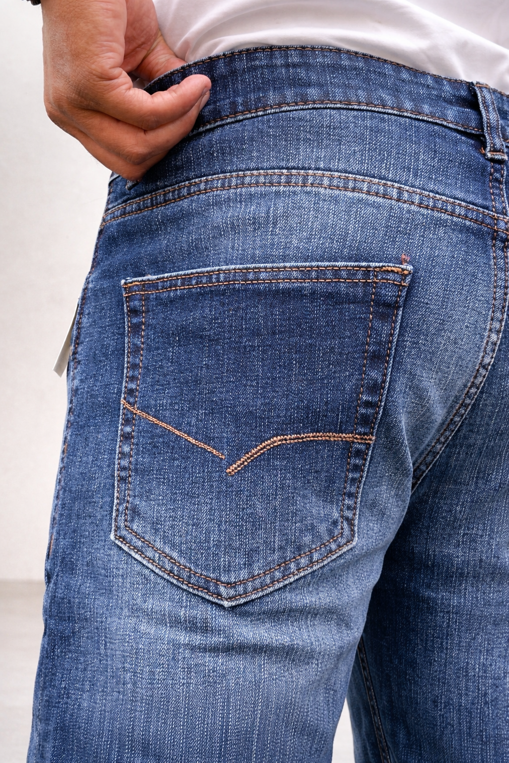 Indigo jeans close-up of back pocket and waistband stitching, back view with label tag.