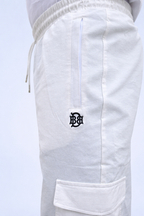White joggers close-up: elastic waist, side pocket with embroidered logo on leg