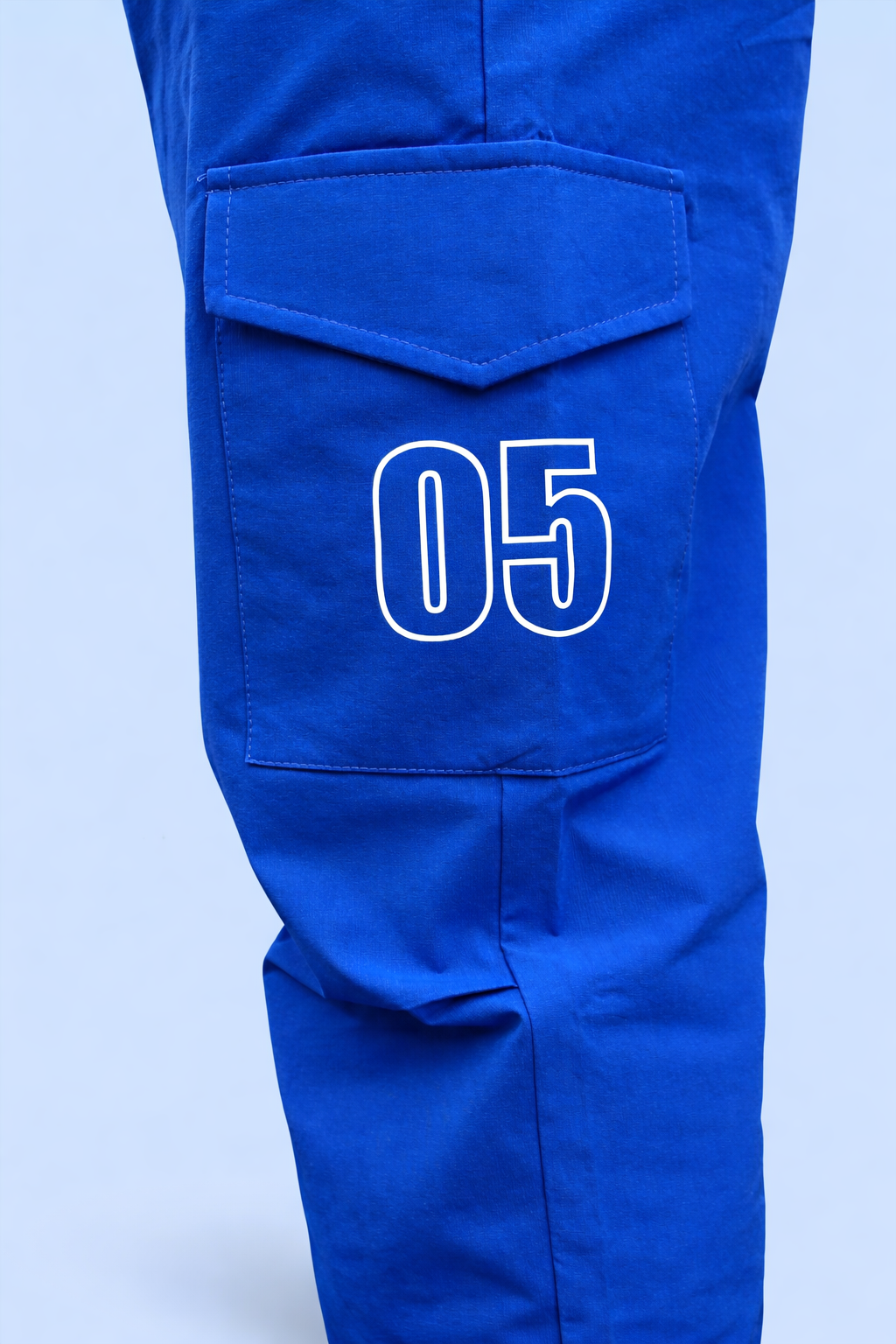 Blue cargo jogger pants close-up of front cargo pocket with “05” patch