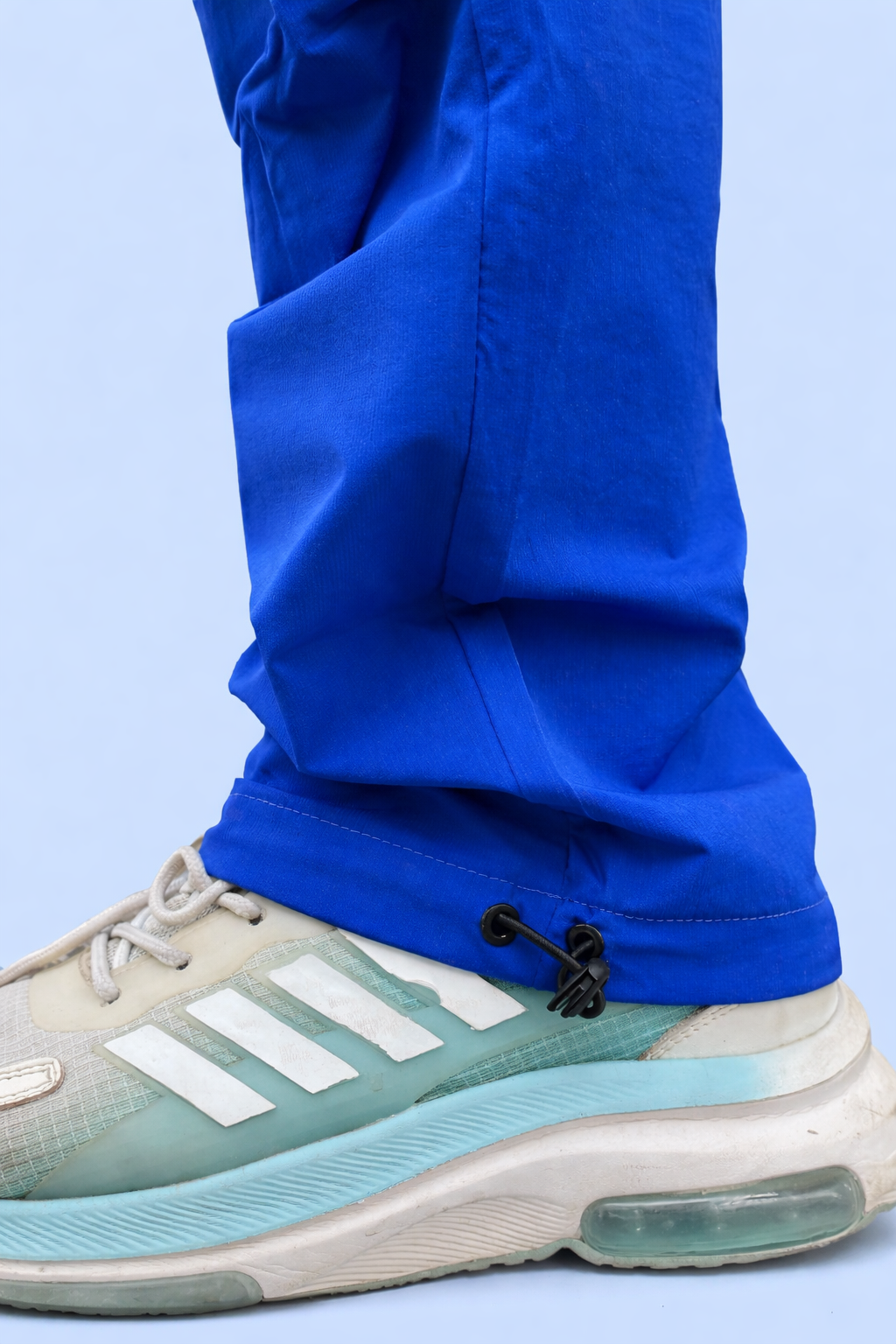 Blue cargo jogger cuff with adjustable strap and drawstring grip, worn with sneakers