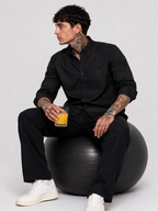 Black oxford button-up shirt with button front and tonal monogram, seated