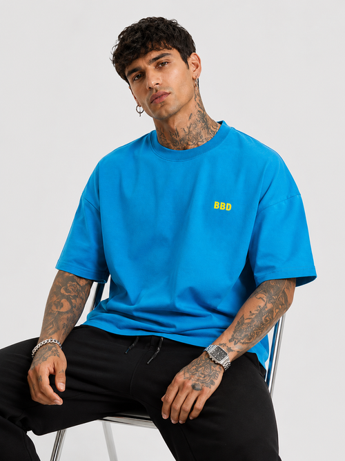 Blue drop-shoulder T-shirt with small yellow chest logo, short sleeves