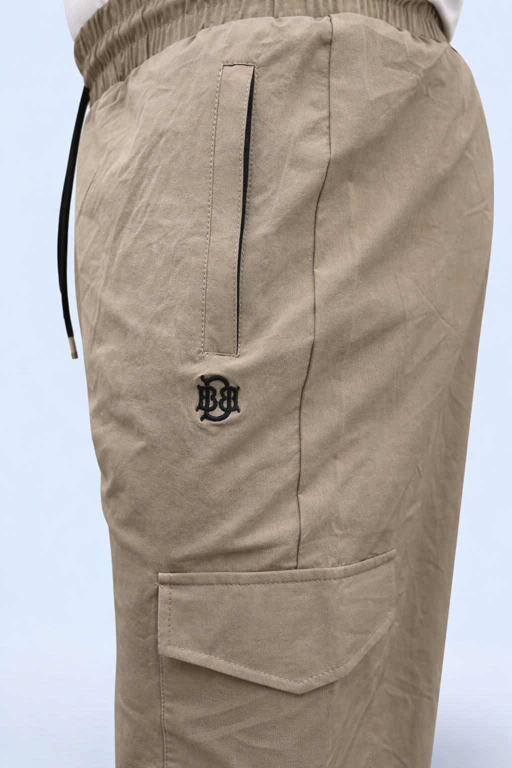 Beige cargo joggers back view with drawstring waist, logo patch, and pocket