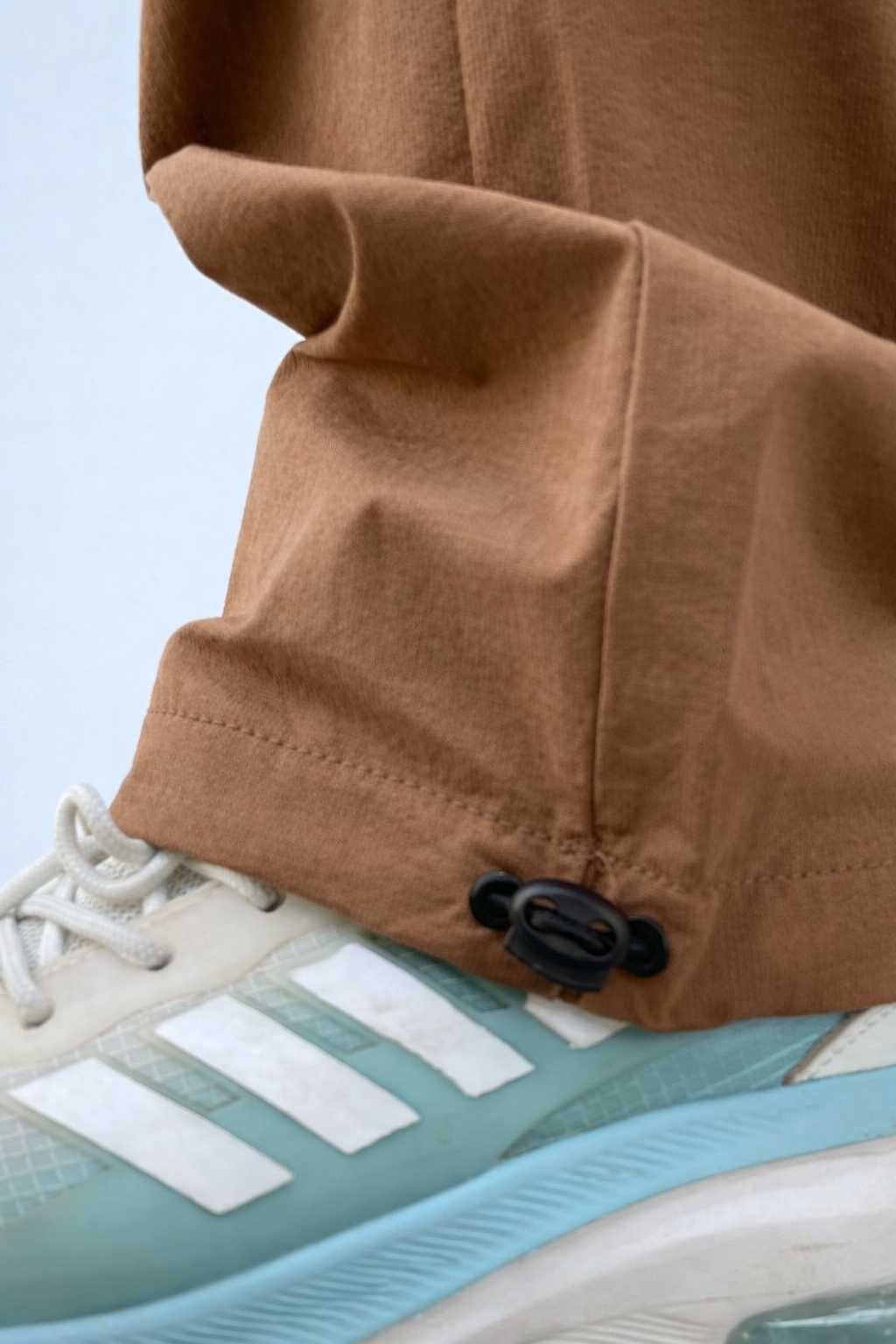 Brown joggers ankle cuff with drawcord and hardware near sneaker