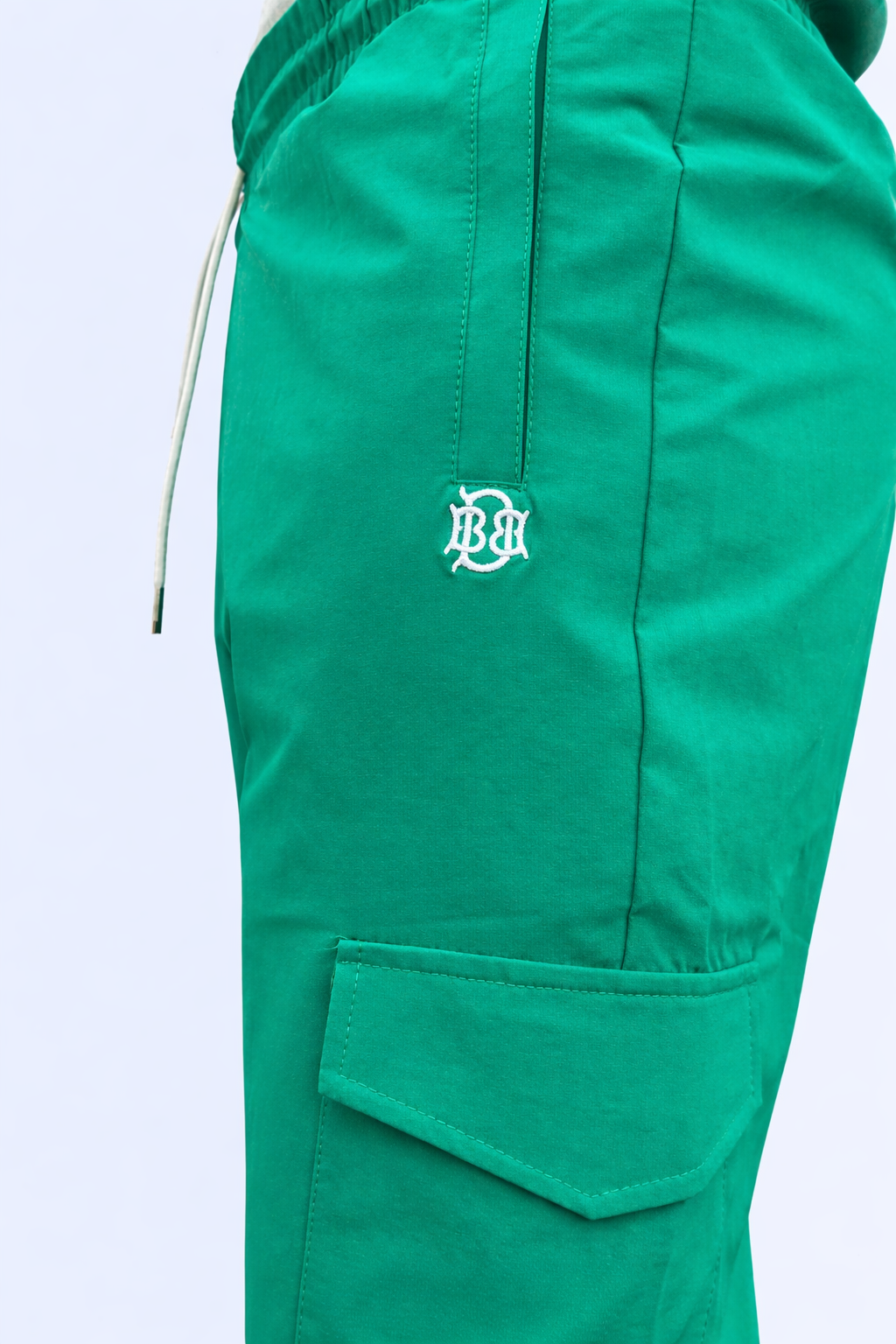 Green jogger pants close-up: BB emblem patch and side cargo pocket