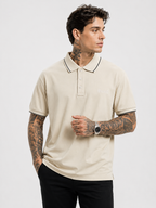 Cream polo shirt with navy-trim collar, button placket, Bradbird logo on chest.