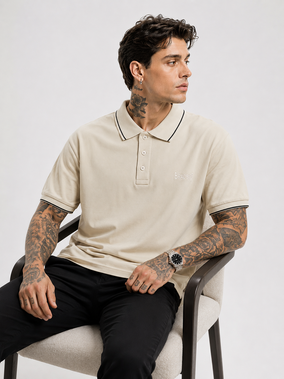 Cream polo shirt with navy-trim sleeve cuffs and collar, Bradbird logo on chest.