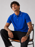 Blue Bradbird polo shirt on model, white tipped collar and sleeve trim
