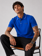 Blue Bradbird polo shirt on model, white tipped collar and sleeve trim