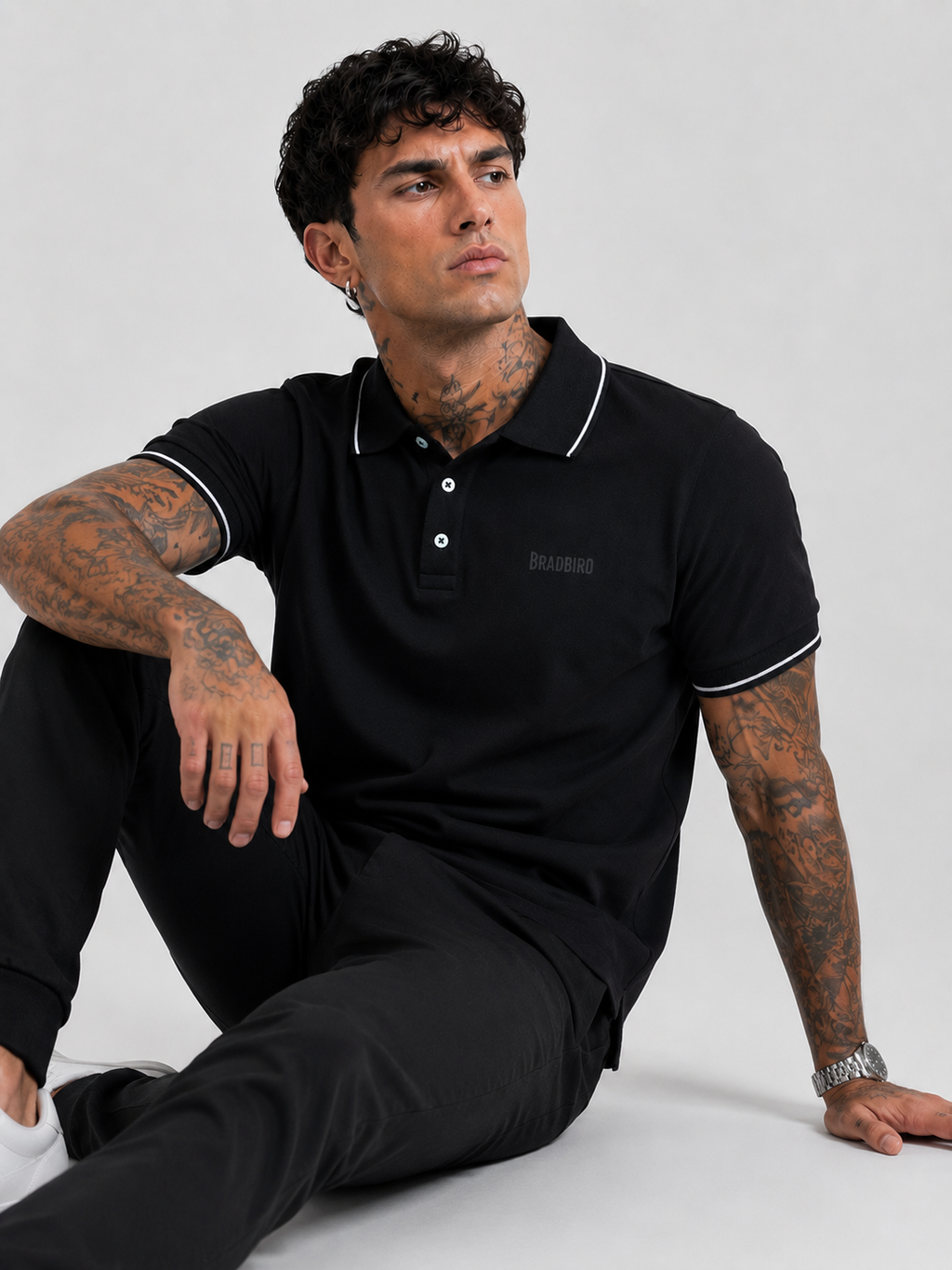 Black polo T-shirt with white dual-tipping collar and short sleeves; Bradbird chest mark.