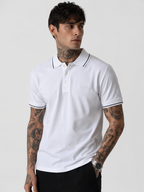 White polo shirt front view, black-trim collar and sleeve cuffs, chest logo detail.