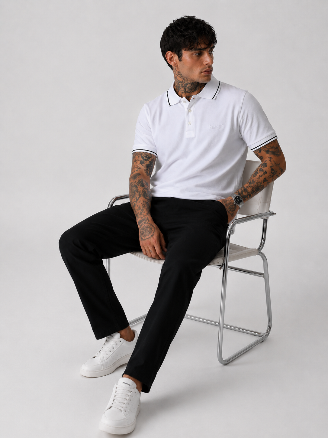 White polo shirt with black collar trim and sleeve cuffs, worn with dark pants.