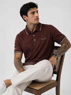 Coffee brown polo shirt with white contrast collar tips and short sleeves, model kneeling.