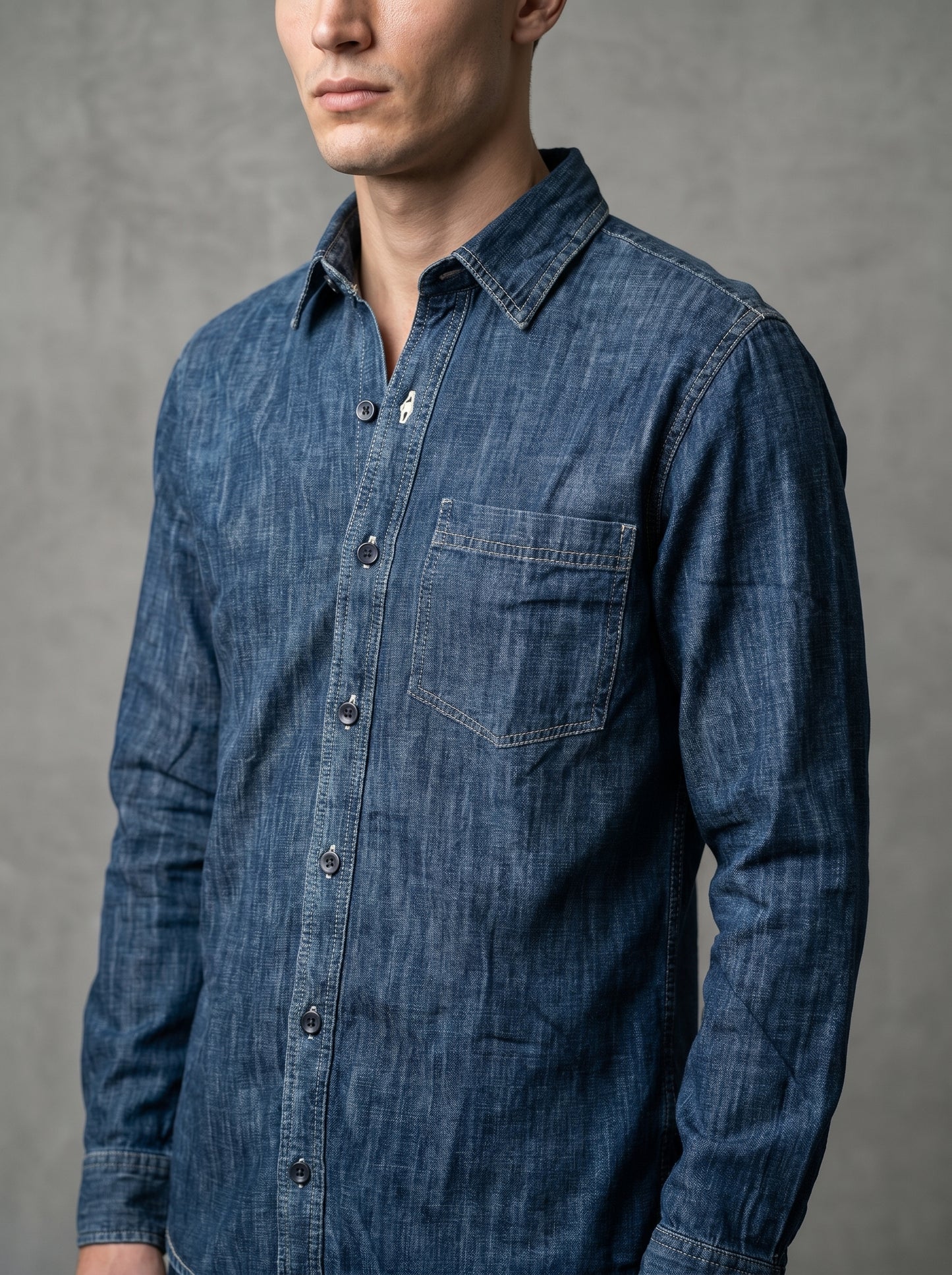 Mid-wash denim shirt with chest pocket and button placket, close side view.