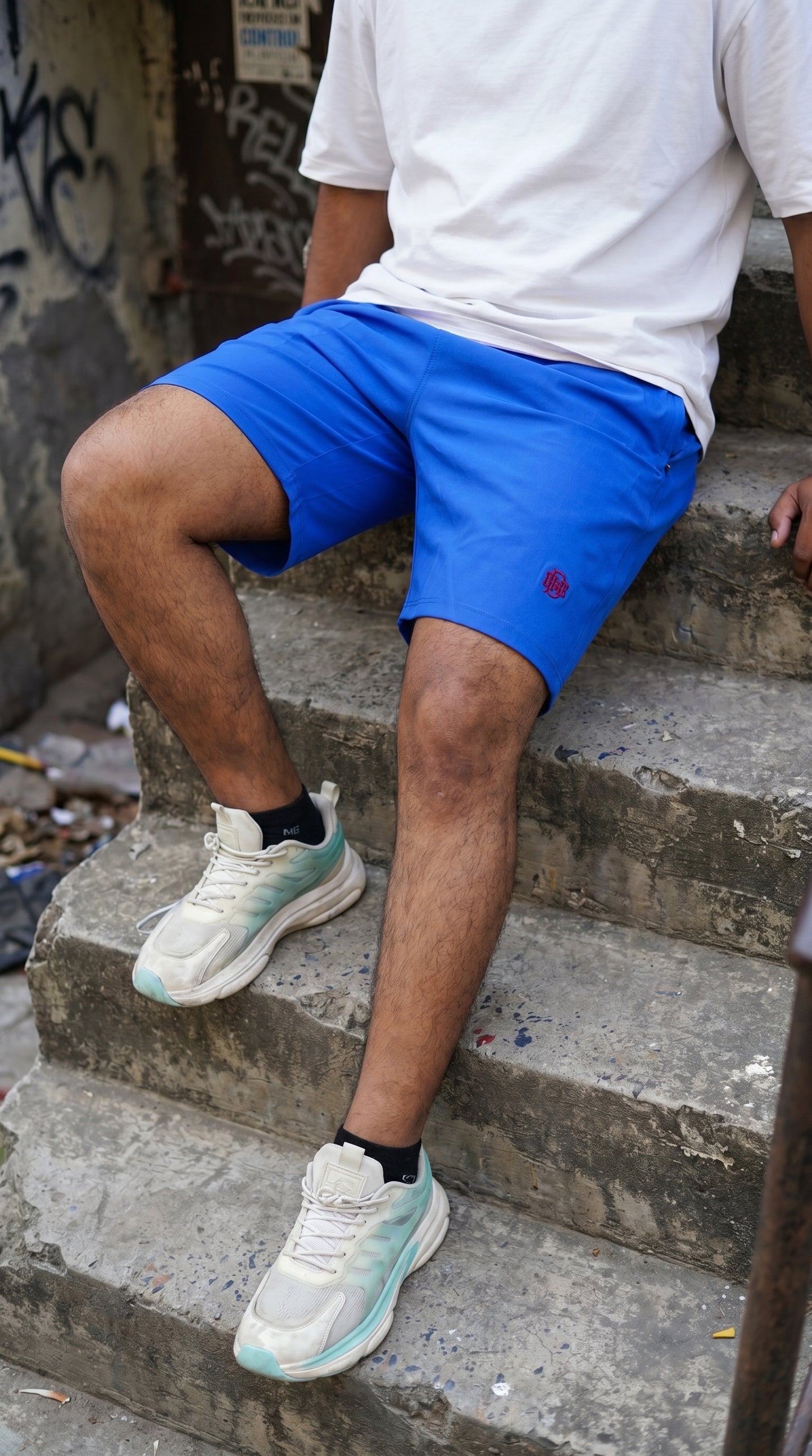 Blue tech shorts with small red logo, relaxed fit, above-knee length