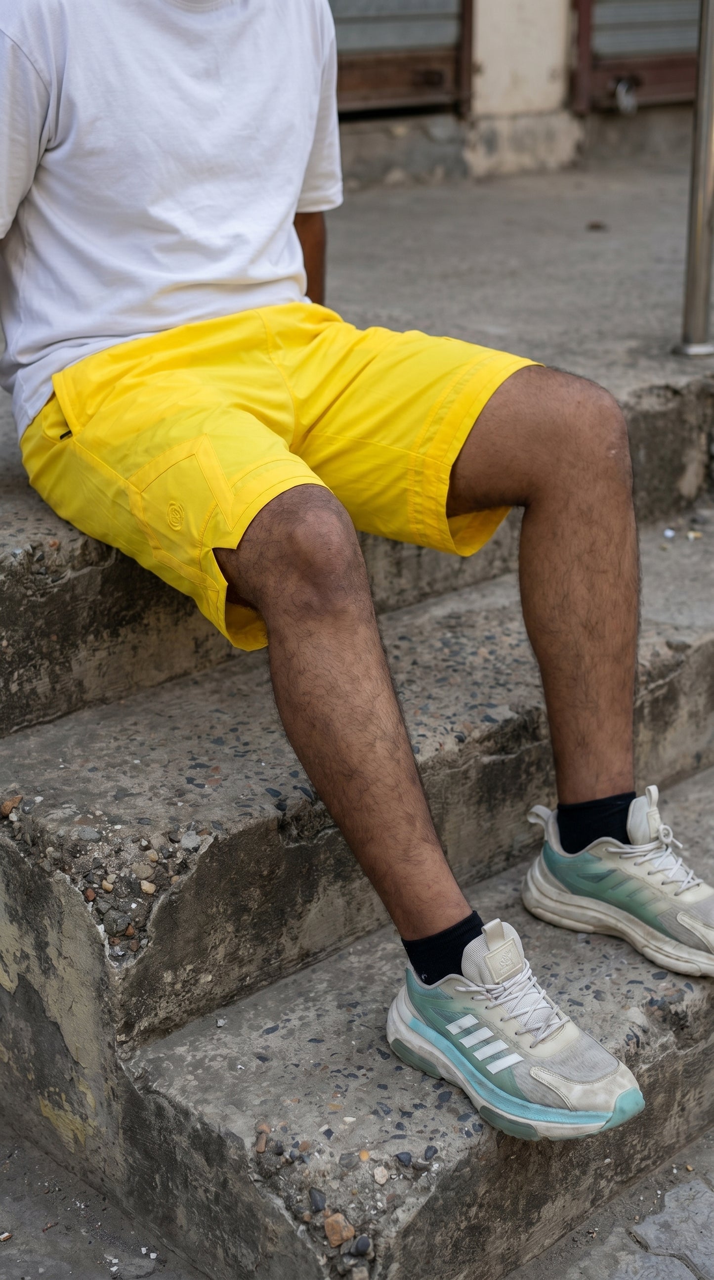 Yellow cargo shorts with pentagonal side pocket detail, cuffed hem