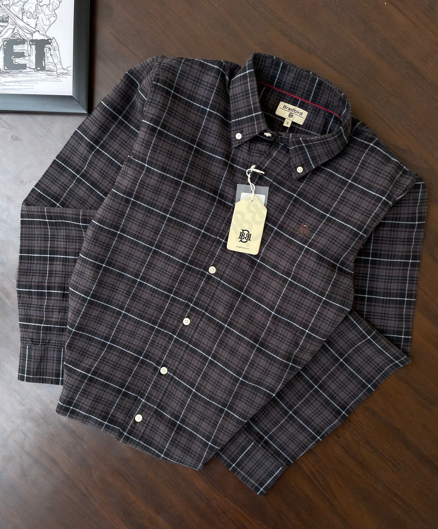 Oxford check button-up shirt laid flat, dark plaid with white lines and front buttons
