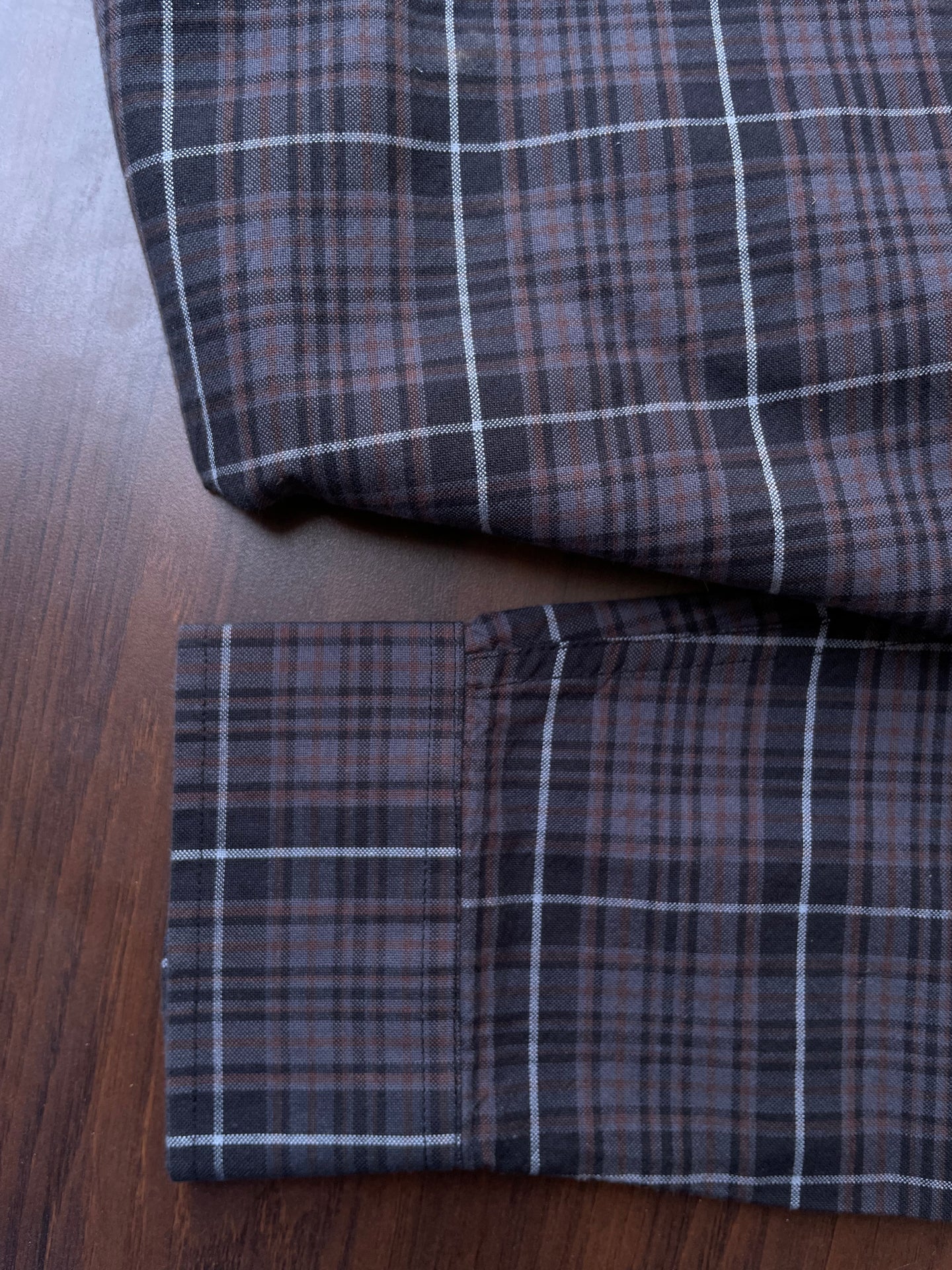 Oxford check shirt fabric close-up: sleeve cuff and hem, dark plaid with white grid