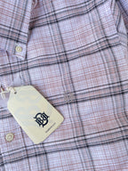 Pink windowpane check oxford shirt fabric close-up with white buttons and hanging tag
