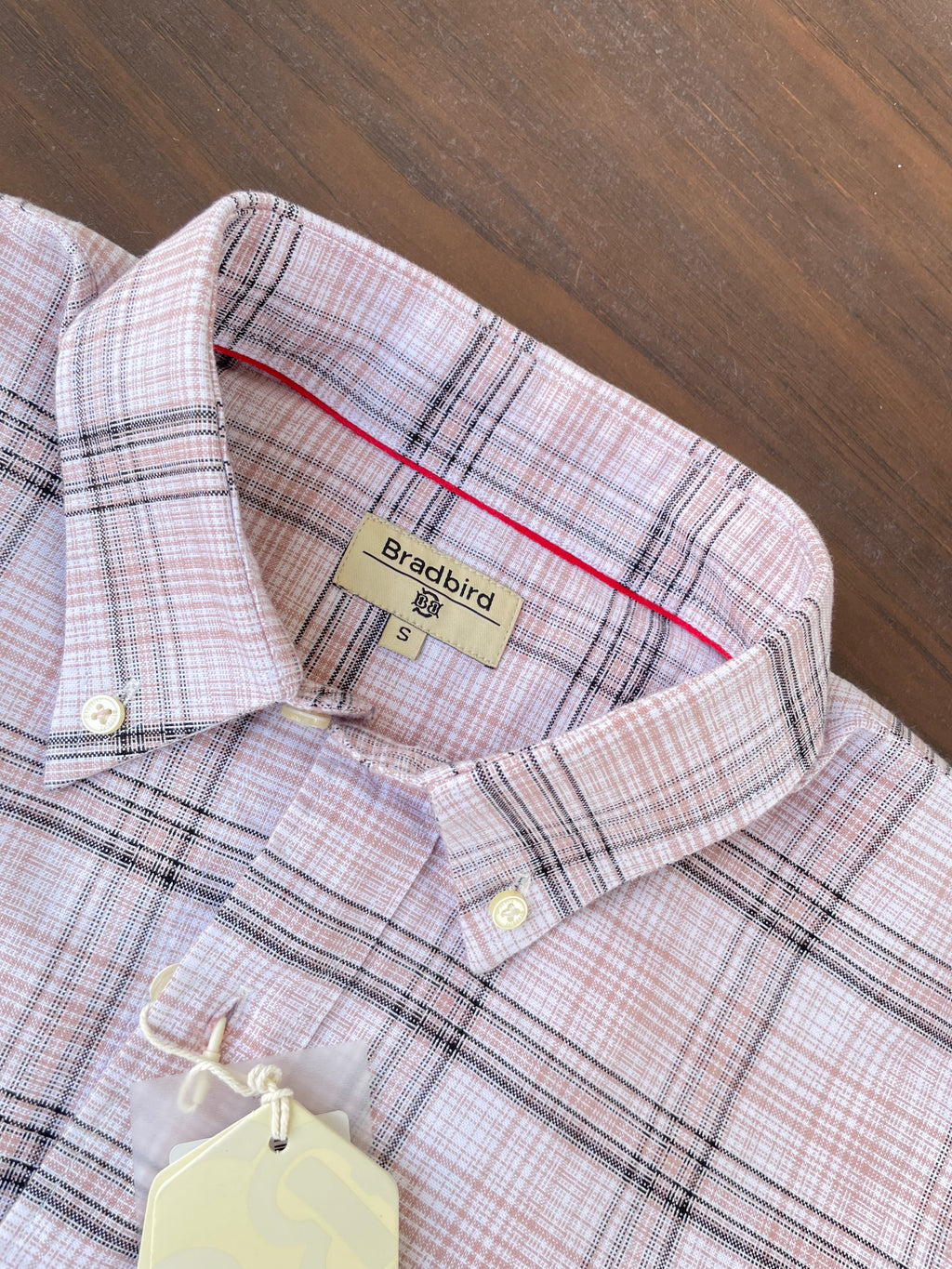 Close-up of pink check shirt neckline with tag and white button placket