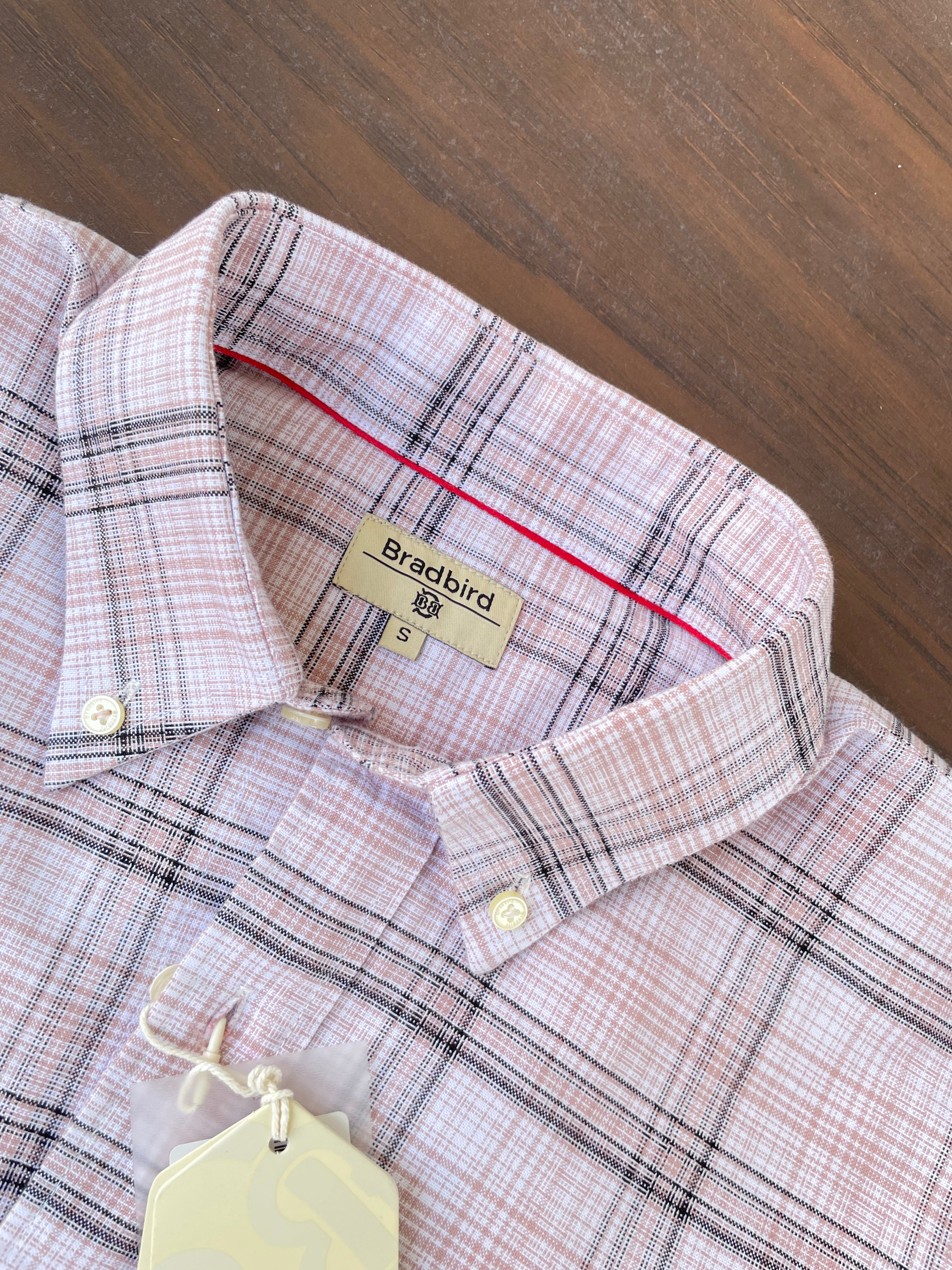 Close-up of pink check shirt neckline with tag and white button placket