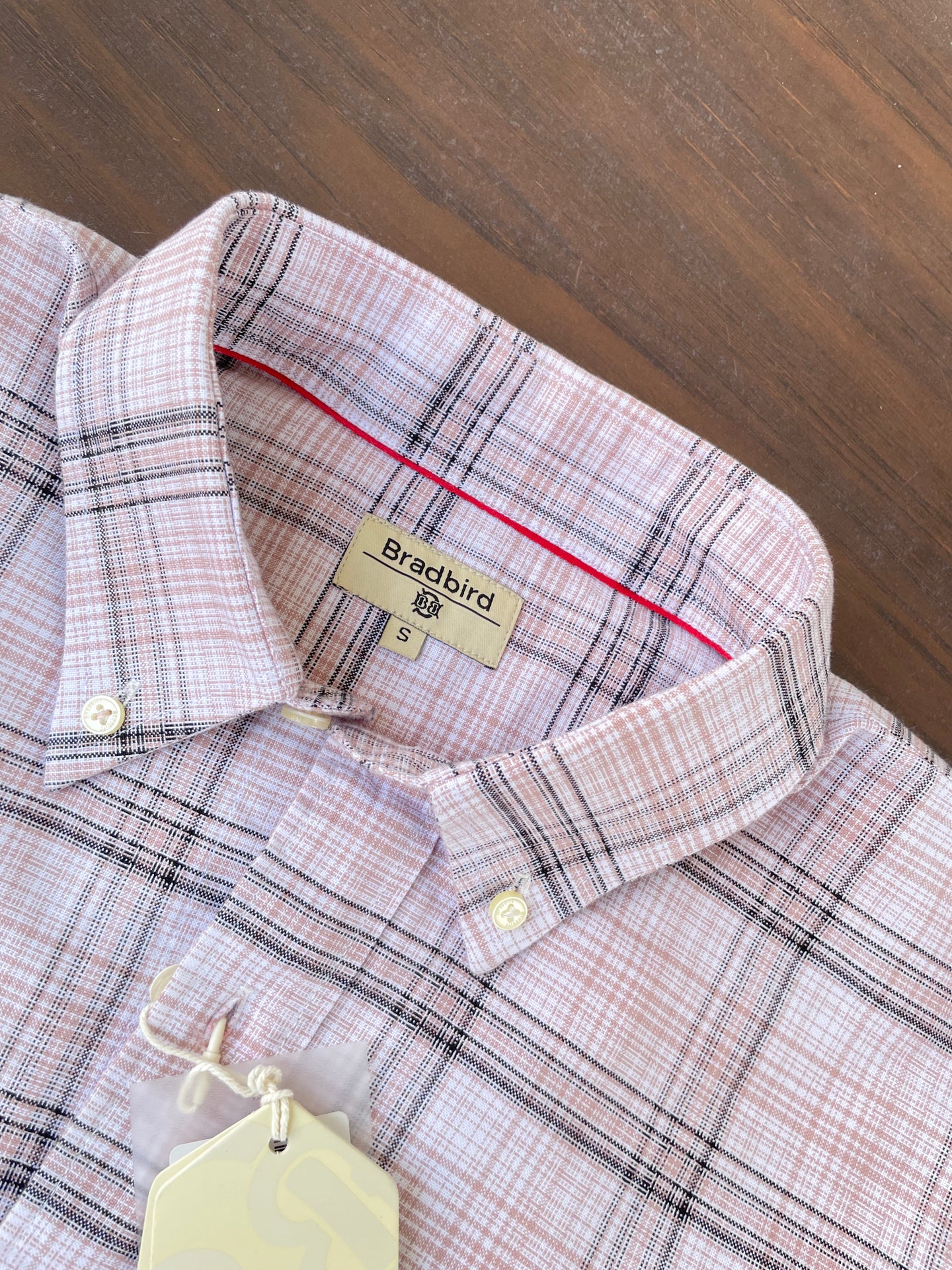 Close-up of pink check shirt neckline with tag and white button placket