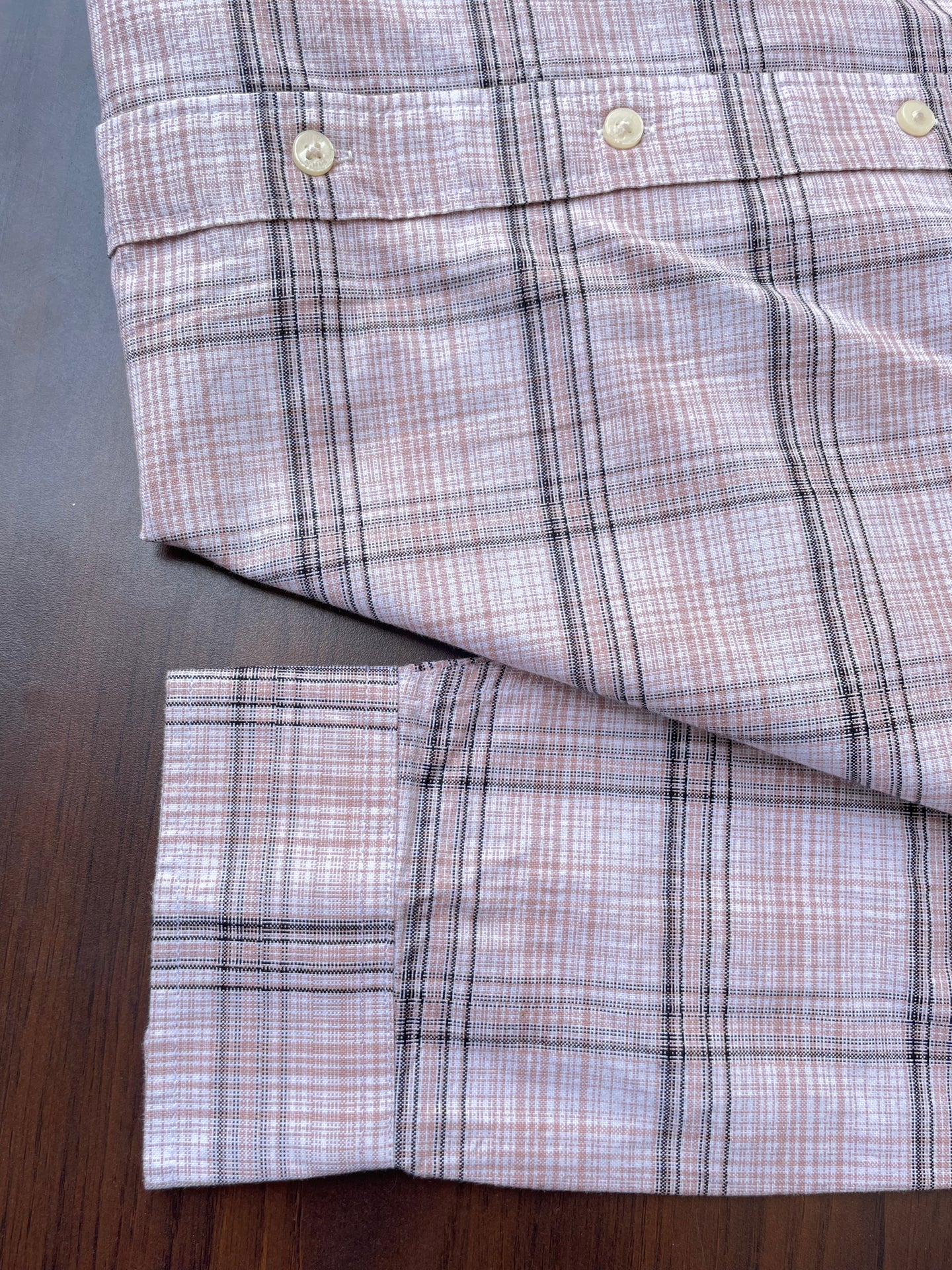 Pink oxford check shirt hem and sleeve cuffs with white buttons, folded