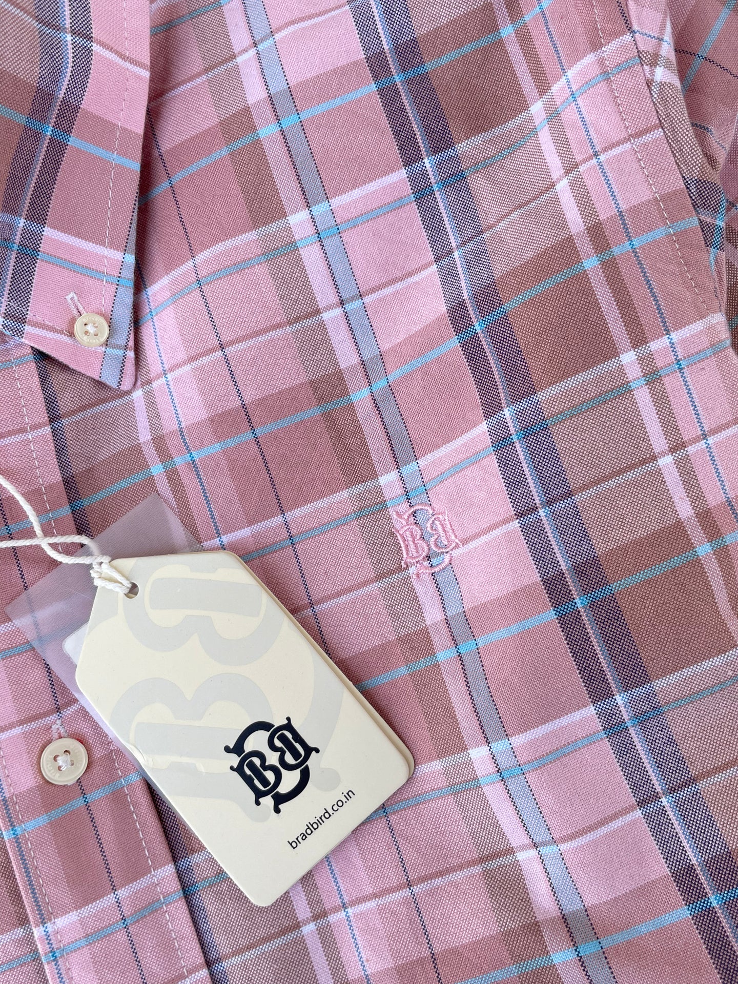 Pink plaid oxford shirt close-up: chest logo patch and button placket