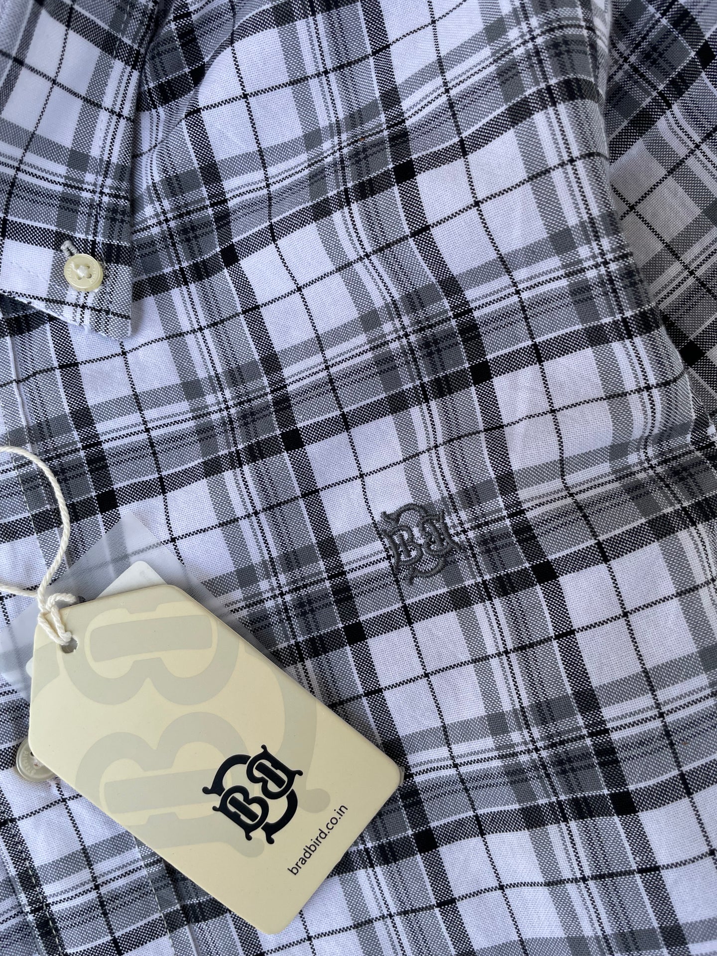 Close-up black-and-white check oxford shirt with chest logo patch and hang tag
