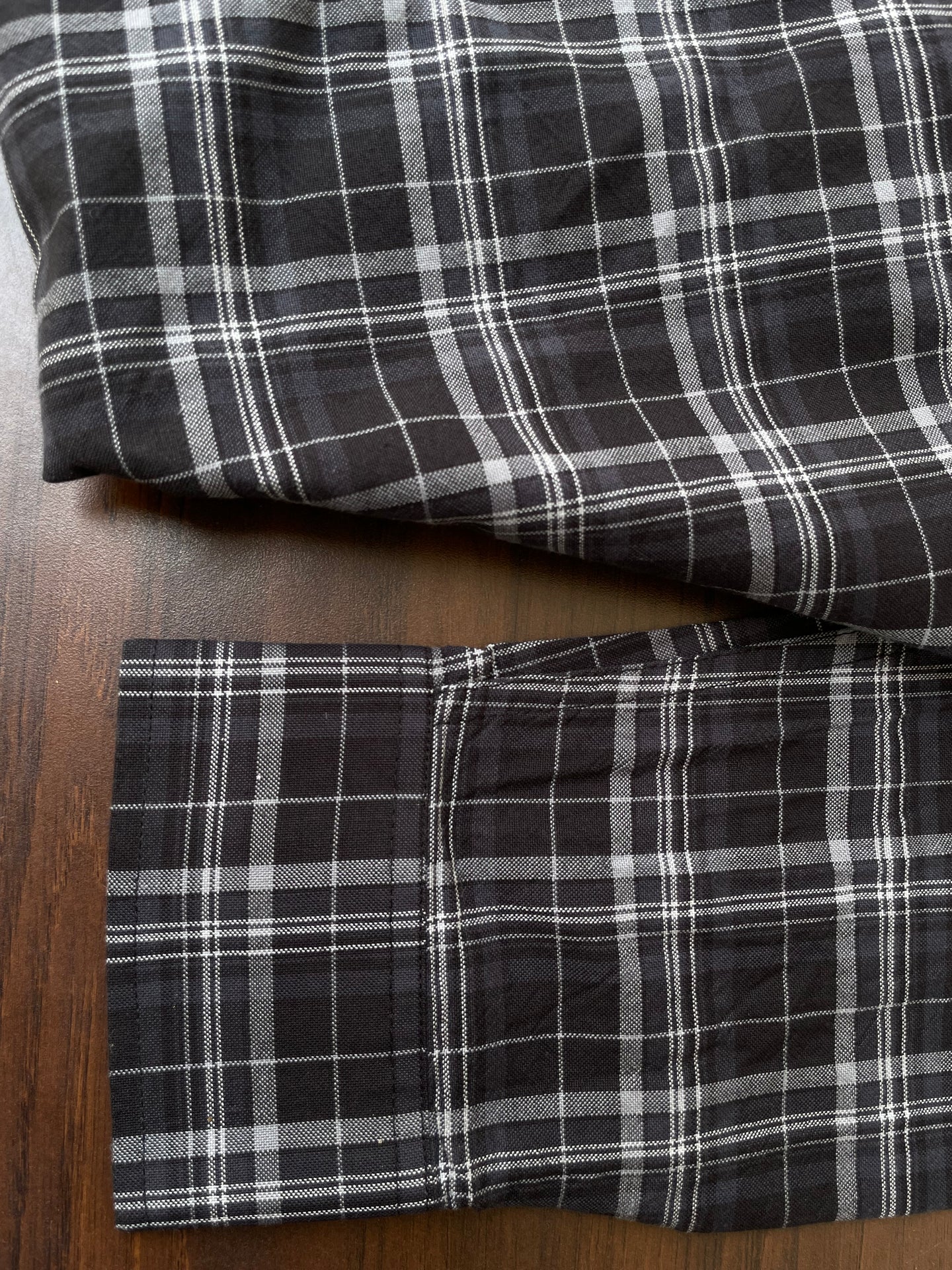 Black plaid shirt cuffs and hem in folded view, stitched check pattern