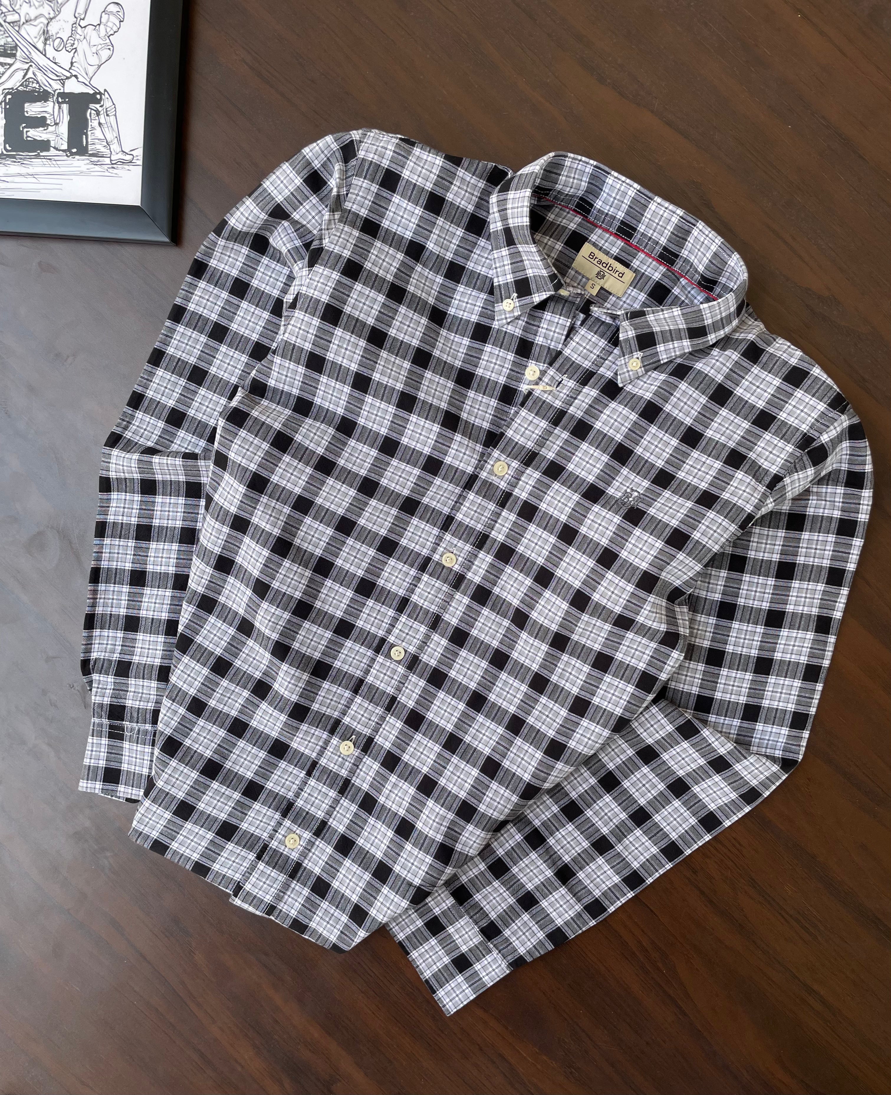 Black-and-white plaid oxford shirt, folded with long sleeves, collar, and buttons
