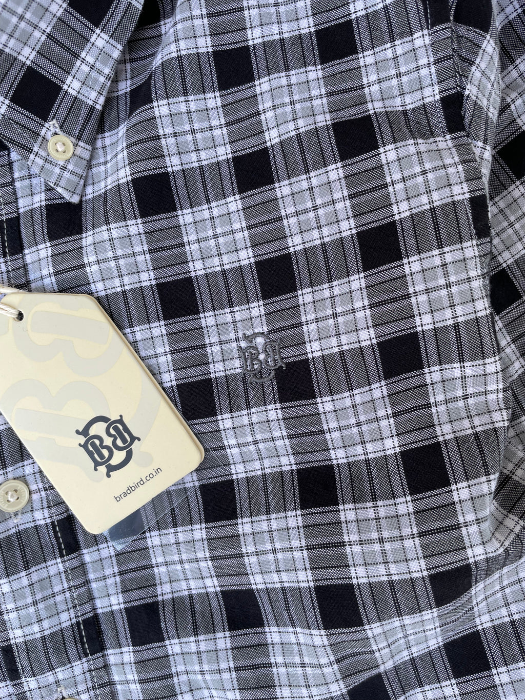 Black-and-white plaid shirt chest detail with small stitched emblem and button