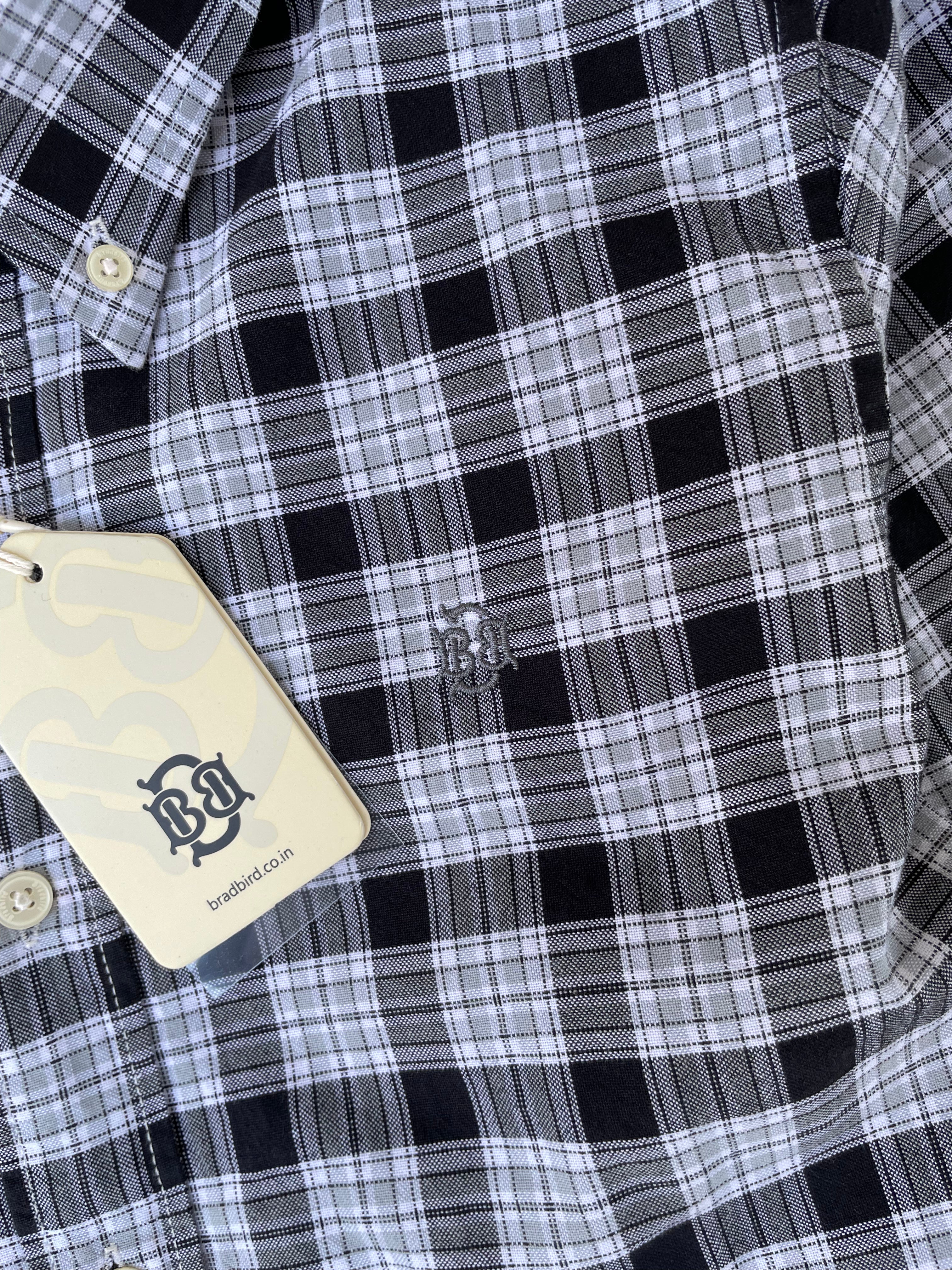 Black-and-white plaid shirt chest detail with small stitched emblem and button