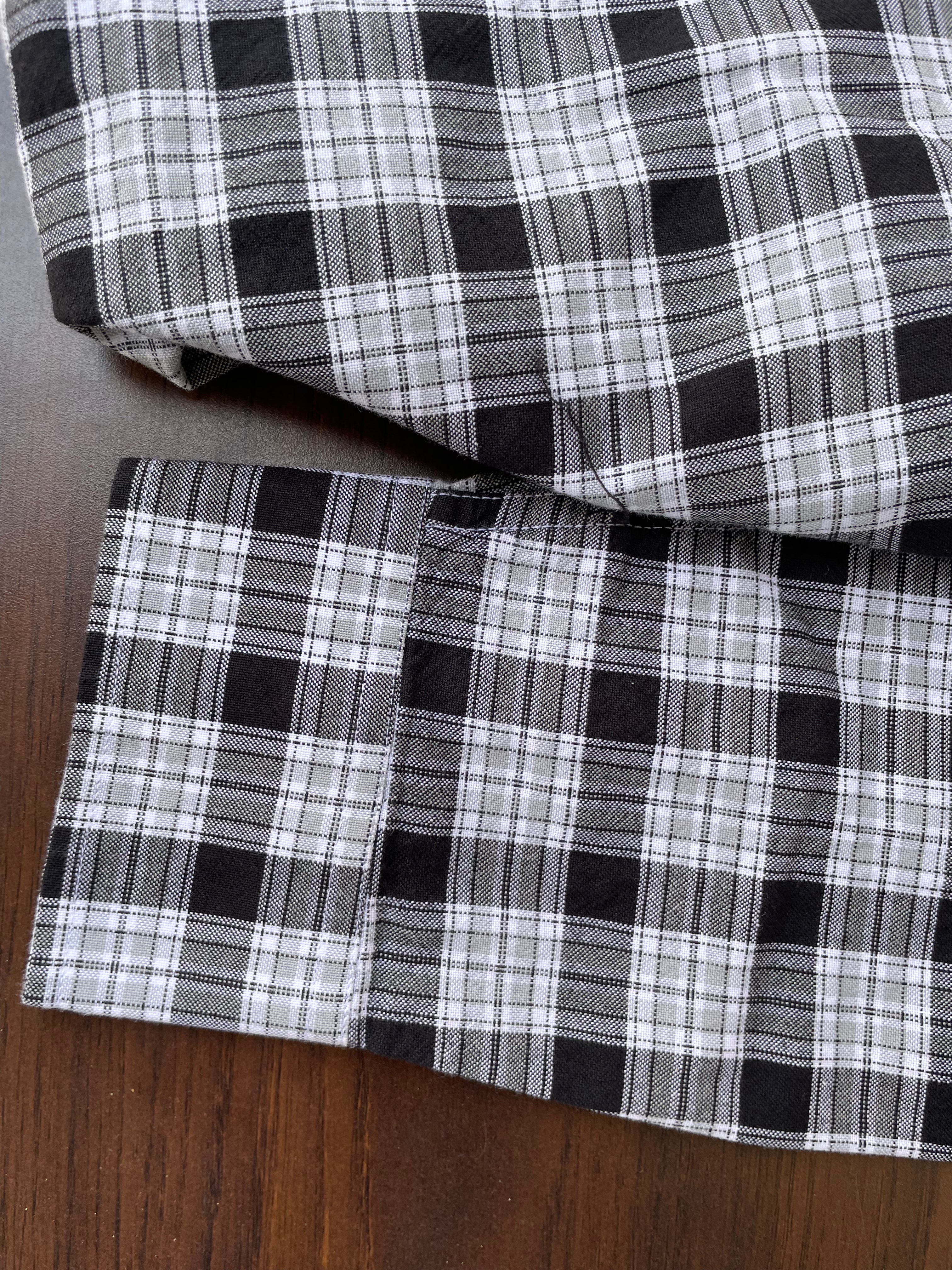 Black-and-white check oxford shirt cuff and hem, showing stitched seams